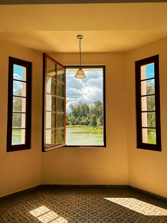 Interior room with an open window overlooking a lake and trees, symbol of openness and reflection
