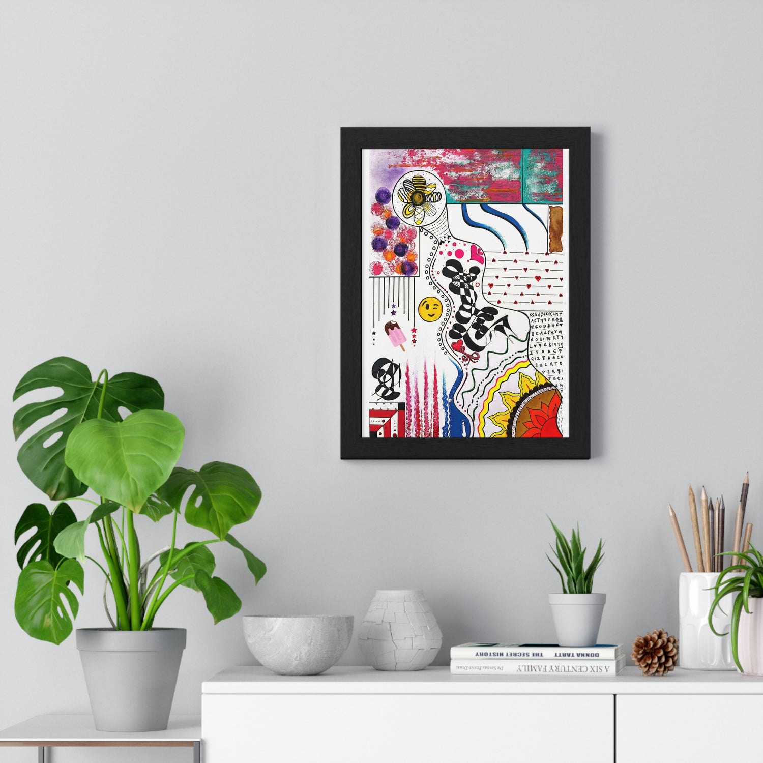 Framed abstract intuitive artwork displayed on a wall above a minimalist shelf with plants